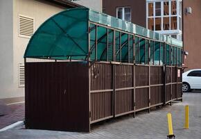 Six new plastic green garbage standard containers. Back side of the city sports festival. In the background - trading canvas tents photo