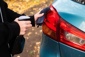 Car disinfection service On a sunny day. A woman disinfects and cleans the inner handle of the car door. Safety and prevention of infection with the Covid-19 virus, infection with microbes or photo