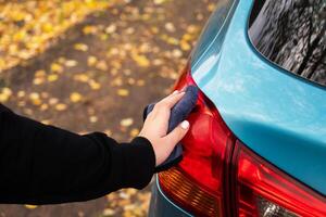 Closeup picture, image young woman, driver, dry wiping her car with microfiber cloth after washing it, cleaning auto, automobile windows. Transportation self service, care concept. Paint protection photo