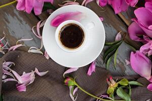 Pink peony flowers and a cup of coffee on a whte background. Morninig, spring, fashion composition. Flat lay, top view, copy space. photo