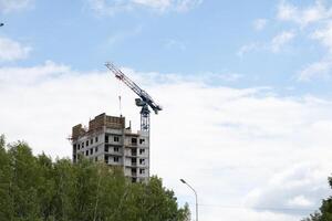 View of the unfinished wall of the house. A construction crane on a blue ky background. photo