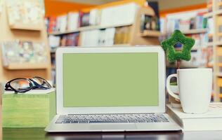 Working at a cozy desk in a bookstore setting with a laptop and coffee during the afternoon photo