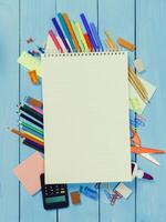 Creative workspace with colorful stationery and a blank notepad on a blue wooden table photo