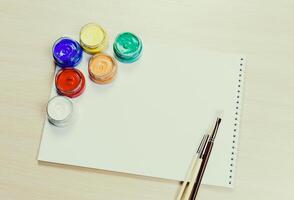 Creative workspace ready for art project with paint pots and brushes on table in bright setting photo