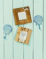 Coastal decor display with wooden frames and shell-shaped hangings on a pale blue wooden background photo
