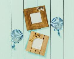 Decoratively designed picture frames and shell shapes arranged on a light blue wooden surface photo
