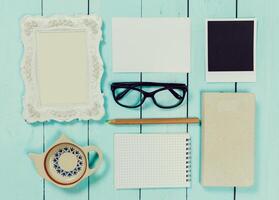 Creative workspace layout with stationery, frames, and a teapot arranged on a wooden table photo