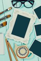 Creative workspace with empty frame, stationery, and coffee cup on turquoise table photo