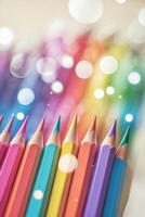 Colorful pencils arranged in a row with soft bokeh highlights, ideal for creative projects and artistic expression photo