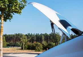 White camper van on a highway rest area with an open hood parked on a roadside for an engine check, indicating trouble or maintenance during a road trip. Copy space 2 photo