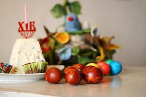 Traditional orthodox easter table with dyed eggs and festive curd paskha, candle, and decorative felted bird nest on the blurred background. Selective focus. 2 photo