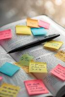 Colorful sticky notes and a pen placed on an open book during a study session in a cozy, well-lit space photo