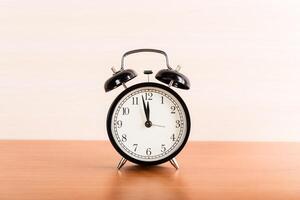 Black alarm clock on the table. Twelve o'clock photo