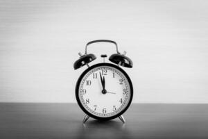 Black alarm clock on the table. Twelve o'clock photo