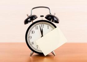 Black alarm clock on the table. Twelve o'clock photo