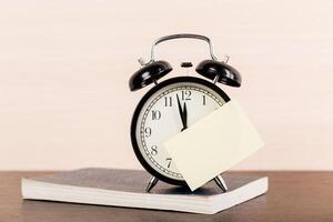 Black alarm clock on the table. Twelve o'clock photo