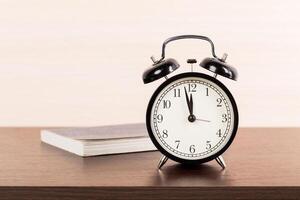Black alarm clock on the table. Twelve o'clock photo