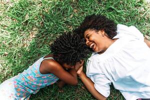 Portrait of mother and daughter lying on the grass happy and smiling. photo