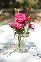 Pink and Red Roses in a Glass Vase on White Floral Pattern Table photo
