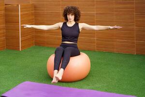 Fitness Exercise A woman expertly balancing on a stability ball within a gym setting photo
