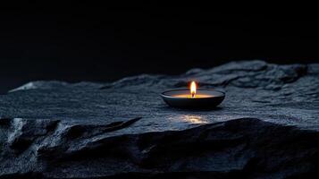 A single candle is lit on a rock photo