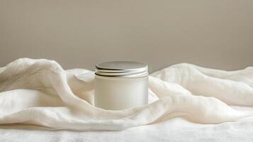 A white jar of cream sitting on top of a white cloth photo