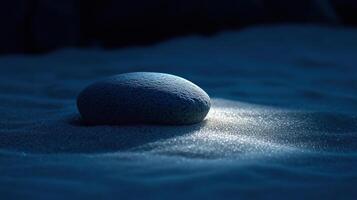 A stone sitting in the sand with a light shining on it photo