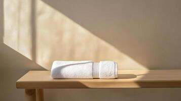 A white towel on a wooden table in front of a window photo