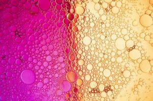 Abstract composition with water and oil drops against magenta and yellow background photo