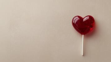 A red lollipop with a heart shape on top of a beige background photo