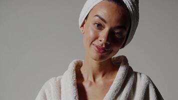 Woman smiling in bathrobe with towel on head in soft lighting video