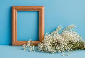 Wooden frame with baby's breath on blue background photo