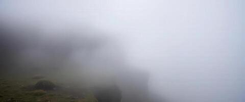 A foggy mountain with a grassy hill in the background photo
