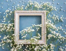 Frame with white flowers on blue wall photo