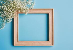 Wooden frame with baby's breath on blue background photo