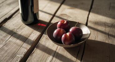 Rustic wooden table with wine and plums in soft light photo