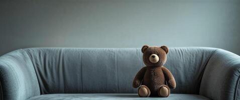 Brown Plush Bear Toy Sitting on Gray Sofa Cozy Home Setting. photo