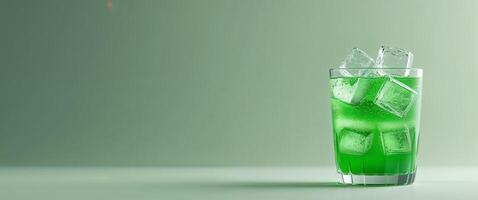 Refreshing Green Beverage with Ice Cubes in a Clear Glass on a Soft Green Background photo
