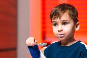Young boy enjoying ice cream at home, a child with a messy face happily savors a spoonful of ice cream while seated indoors with warm lighting. photo