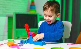 Child plays with colorful toys. A young boy happily engages with a colorful toy set, exploring creativity while seated at a bright table. photo