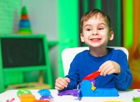 Child playing with colorful toys. A young boy smiles brightly while playing with vibrant toys at a table, showcasing joy and creativity. photo