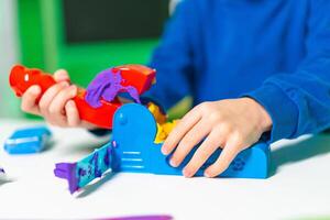 Kid plays with bright clay set. A child molds colorful clay into shapes using a playful molding tool on a bright table. photo