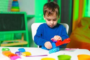 Child loves colorful dough play. A young child engages in creative activities with vibrant modeling dough, focused on molding and shaping various colors. photo