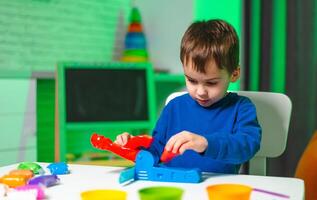 Child playing with bright toys. A young boy plays with bright toys in a well-lit room, focused on a colorful activity with various shapes nearby. photo