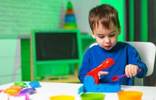 Child plays with colorful clay. Child engages in creative play with bright modeling clay on a table, enjoying hands-on activities in an inviting space. photo