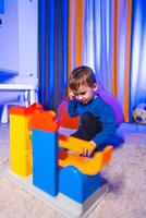 Boy playing with vibrant blocks. A small child engages creatively with vibrant building blocks in a cozy indoor space filled with soft lighting. photo