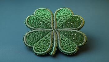 Green four-leaf clover patch. This detailed green four-leaf clover is beautifully embroidered on a textured surface, showcasing intricate patterns. photo