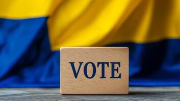 Boosting voting engagement. A wooden block with VOTE is set against a yellow and blue flag, symbolizing democracy. photo