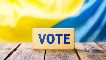 Promoting voting participation. A wooden block with 'Vote' sits on a rustic table, set against a colorful backdrop of civic pride. photo