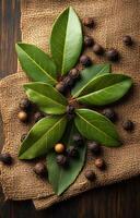 Bay leaves and whole spices. Bright green bay leaves are arranged with whole spices on burlap fabric in a rustic setting. photo